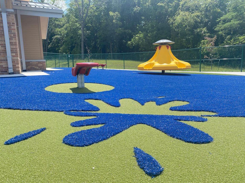 Closeup of a playground surfacing with a design and blue and green turf