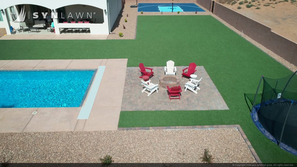 Backyard with clean artificial grass and a clear blue pool with squared edges