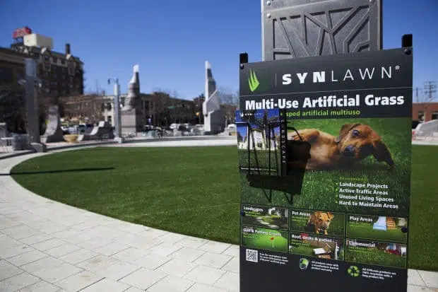 An advertisement for SYNLawn artificial grass is displayed in front of the new turf at Main Street Square