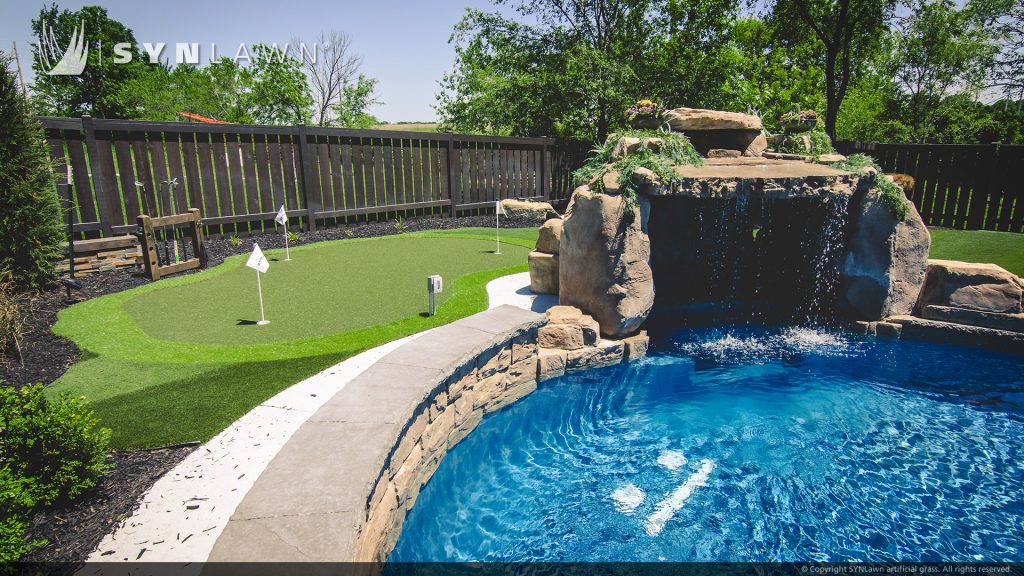 image of residential backyard with striped artificial grass and putting green
