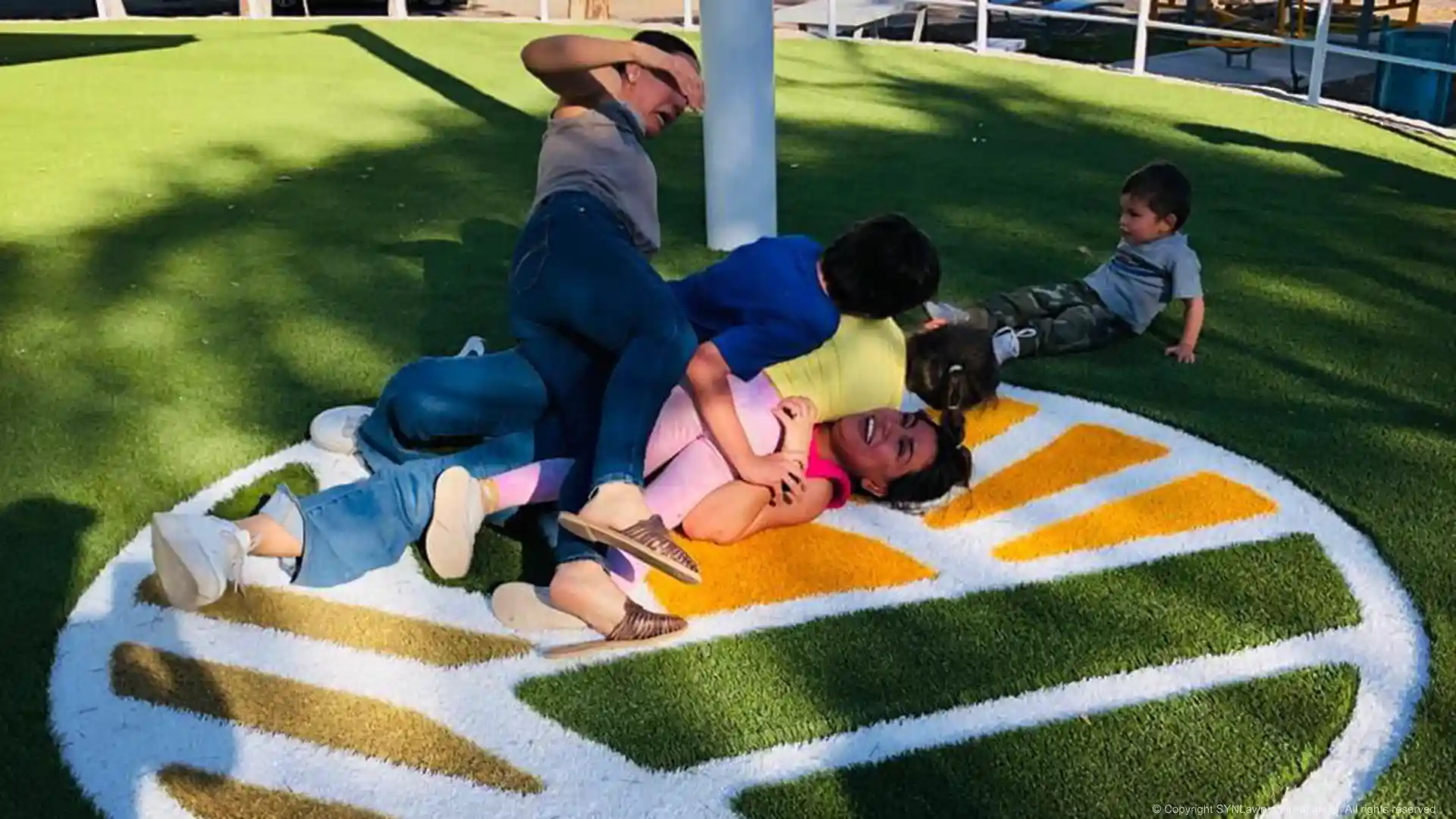 Artificial grass safe for children and families in Aldama, Guanajuato, México image of family playing on child safe artificial grass with custom logo in aldama guanajuato méxico